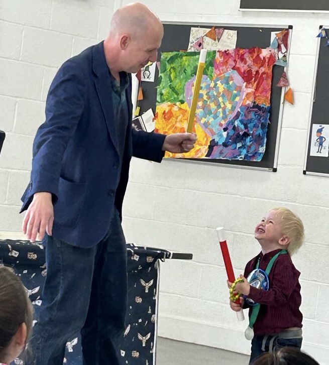 Pete Hare performing children's magic — a young guest laughing with delight at a Surrey birthday party